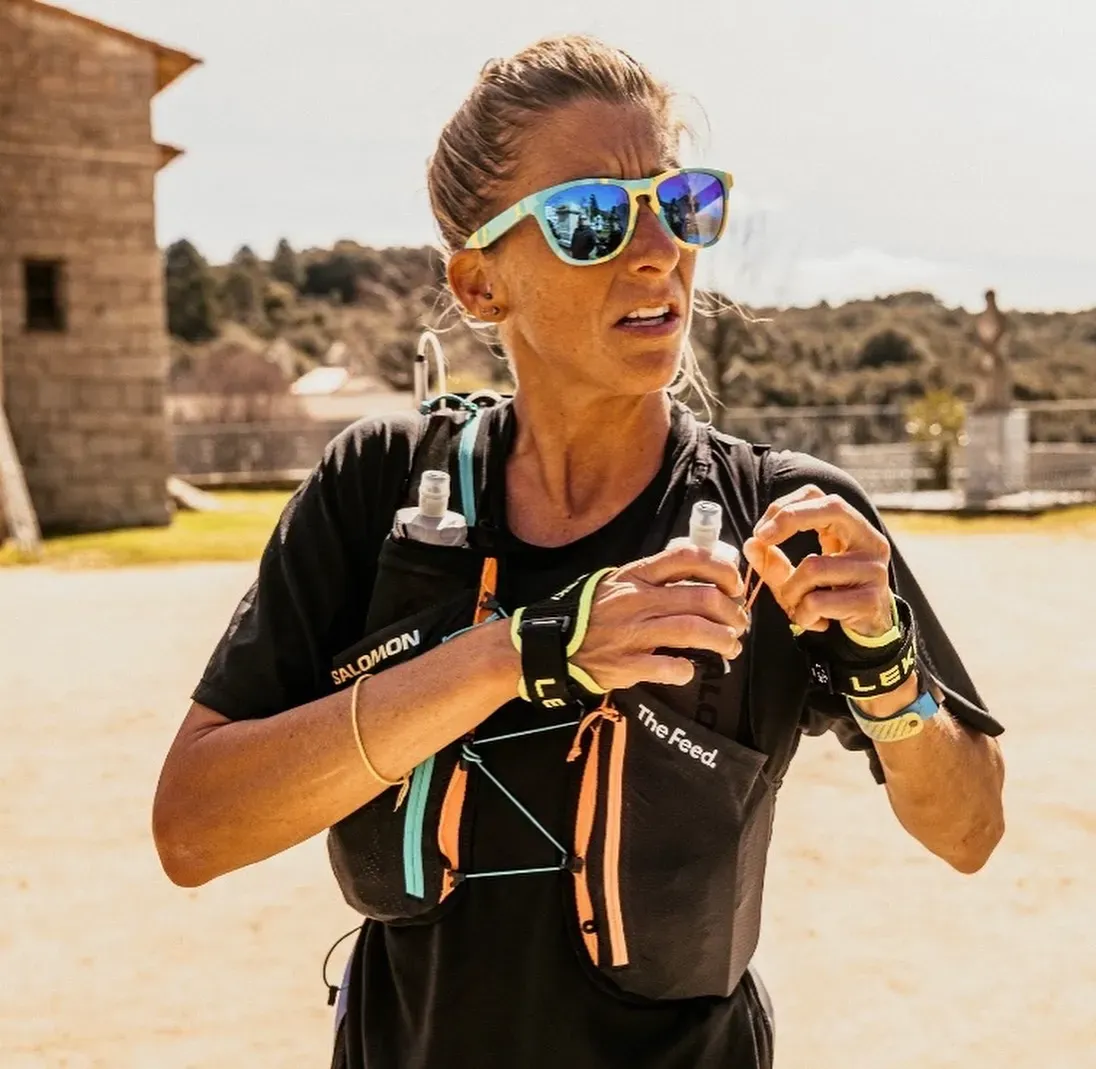 Ultrarunner Courtney Dauwalter wearing mirrored sunglasses and a hydration vest during an outdoor race